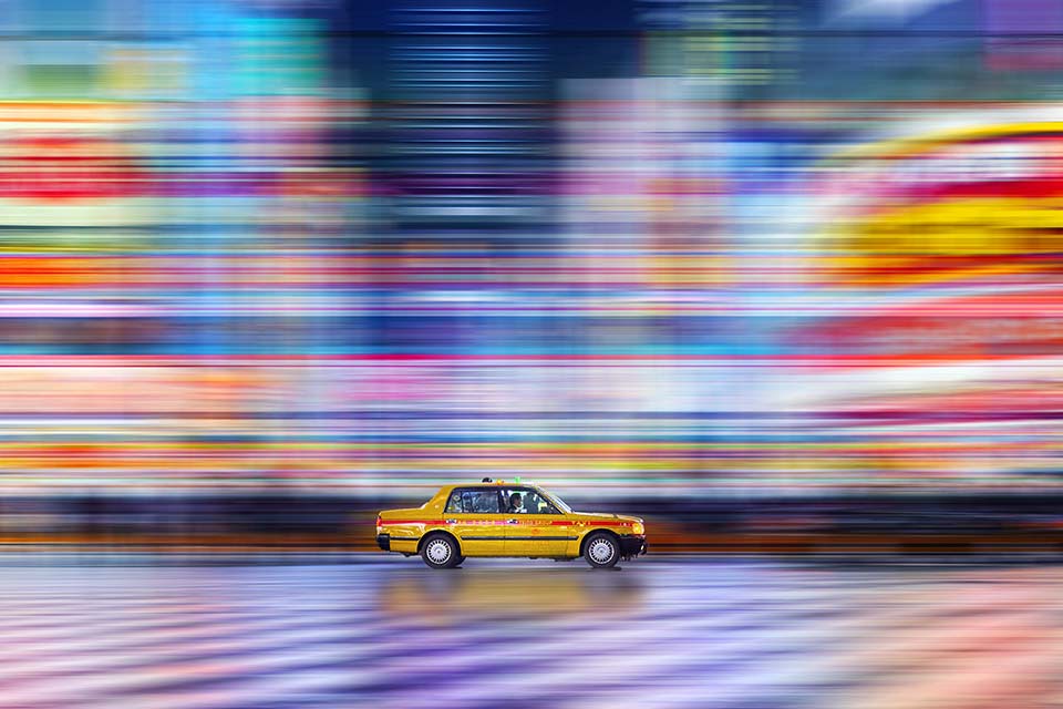 A motion blurred street with an in-focus taxi.